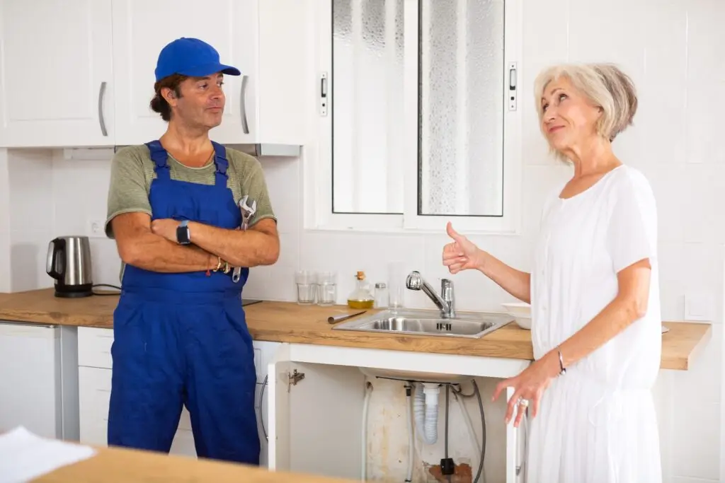 Elderly,Woman,Thanking,Professional,Plumber,For,Work,In,Home,Kitchen