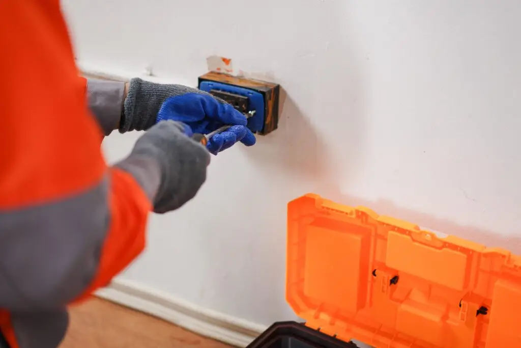 An,Electrician,Wearing,Safety,Gear,Is,Installing,An,Electrical,Outlet